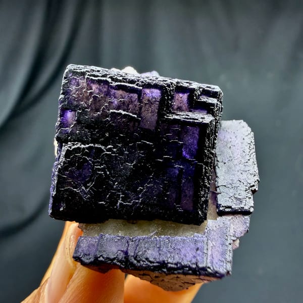 QR-code purple-framed fluorite cube glowing when, from Inner Mongolia, China, front view in daylight, held in hand