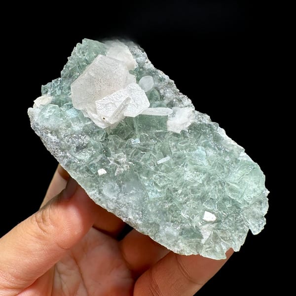 White platy calcite on mint-green fluorite block from Fujian, China, held in hand