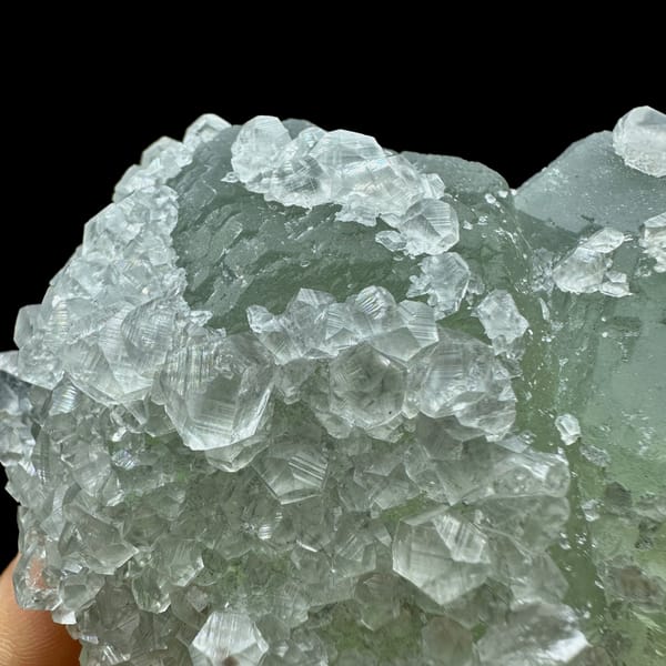 Pale green fluorite balls under white calcite frosting from Fujian, China, close-up of the crystal faces