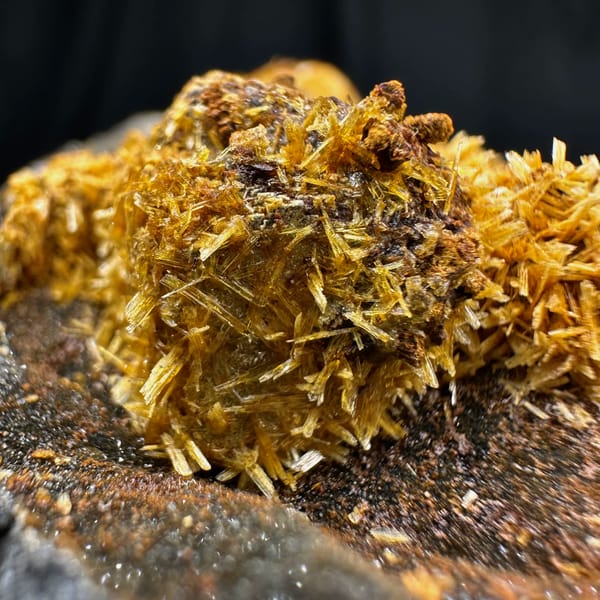 Golden jarosite balls over fluorite on dark plate from Guizhou, China, close-up of the crystal faces