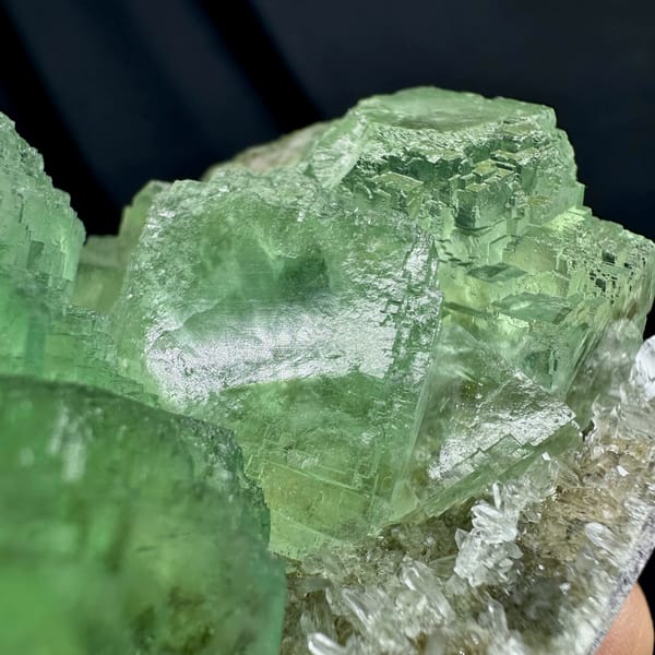 Glassy green fluorite cubes on white quartz druse from Fujian, China, close-up of the crystal faces