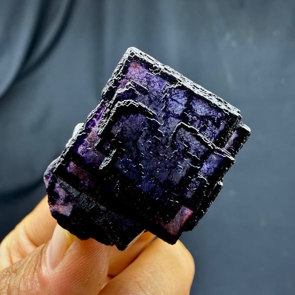 QR-code purple-framed fluorite cube glowing when, from Inner Mongolia, China, front view in daylight, held in hand