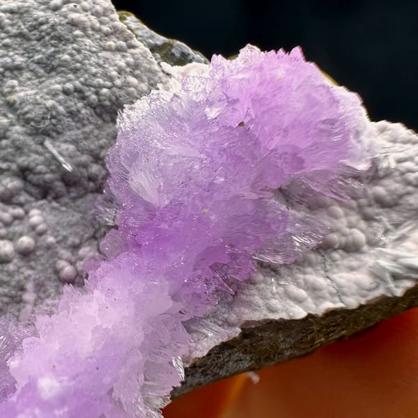 Pink aragonite band across pale grey matrix from Yunnan, China, close-up of the crystal faces