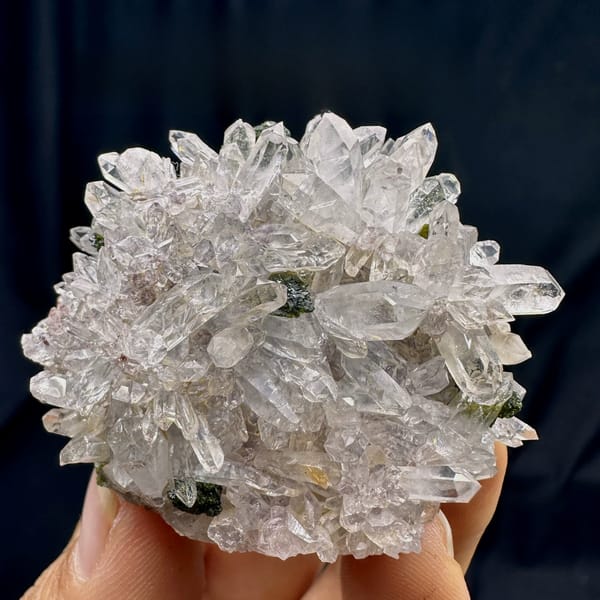 Rounded cluster of sparkling clear quartz with epidote from Sichuan, China, held in hand