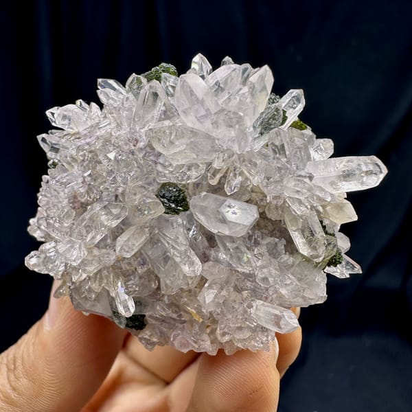 Rounded cluster of sparkling clear quartz with epidote from Sichuan, China, close-up of the crystal faces