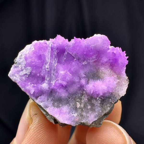 Vivid violet aragonite with clear gypsum blade from Yunnan, China, held in hand