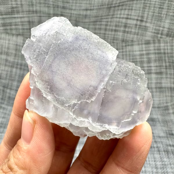 Large purple-framed fluorite crystal with frosted skin from Guangxi, China, held in hand