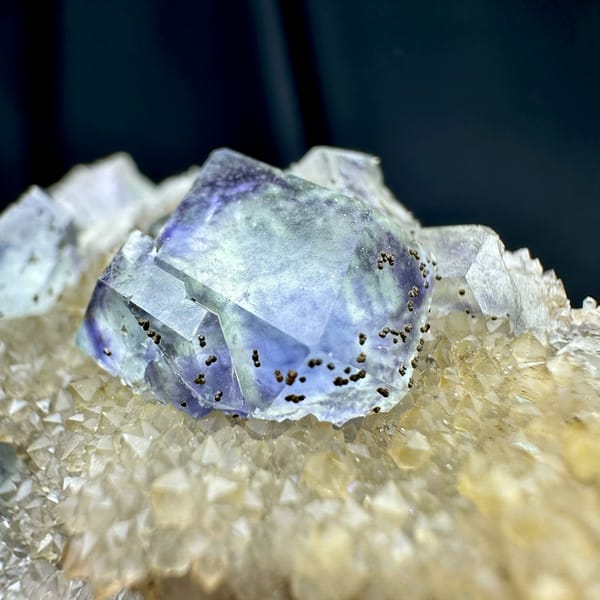 Lavender-blue fluorite dodecahedra with pyrite on quartz druse from Fujian, China, close-up of the crystal faces