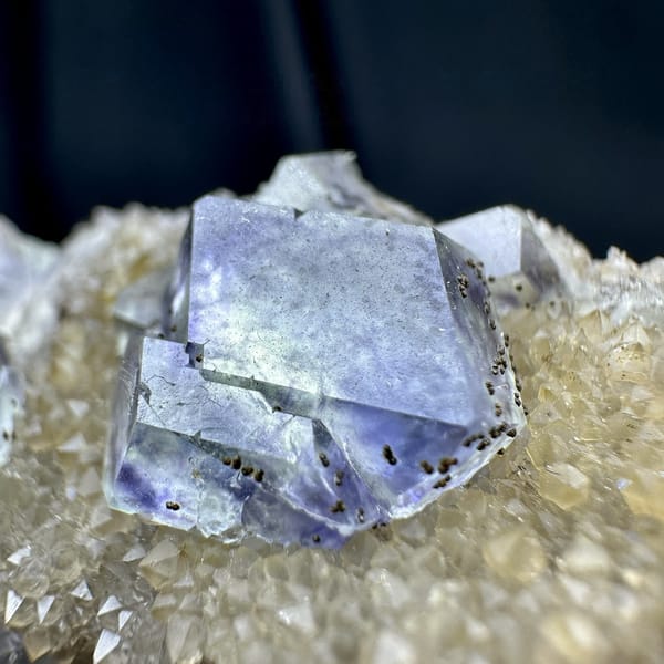 Lavender-blue fluorite dodecahedra with pyrite on quartz druse from Fujian, China, detail of the matrix contact