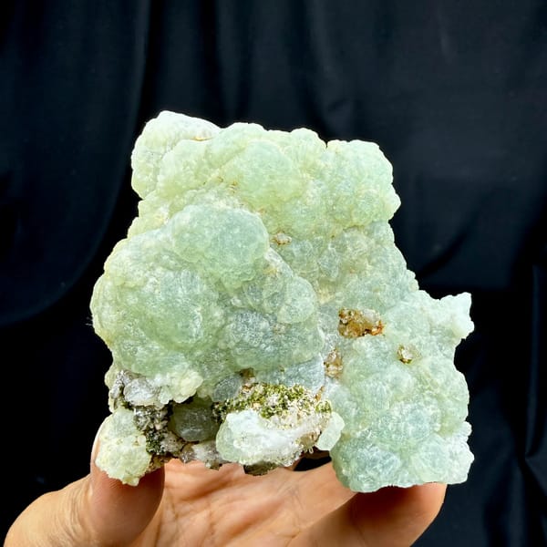 Mint-green prehnite balls with epidote and quartz from Sichuan, China, held in hand