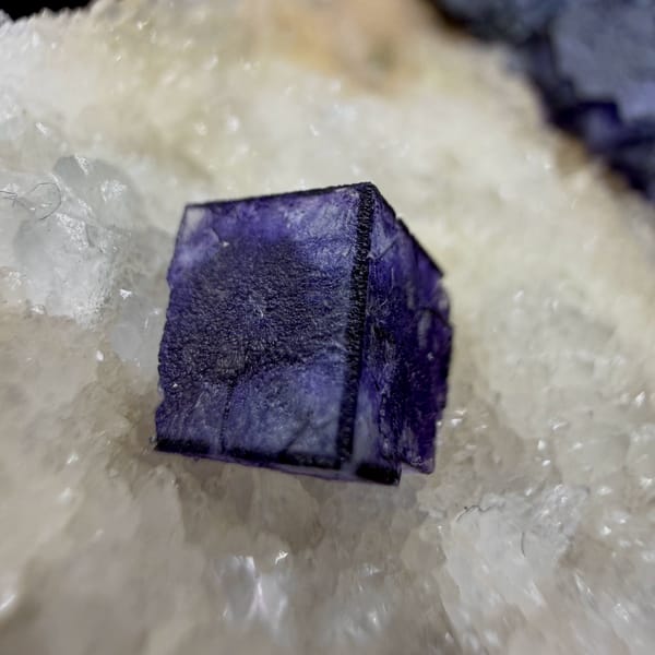 Two deep purple fluorite cubes on white quartz plate from Inner Mongolia, China, close-up of the crystal faces