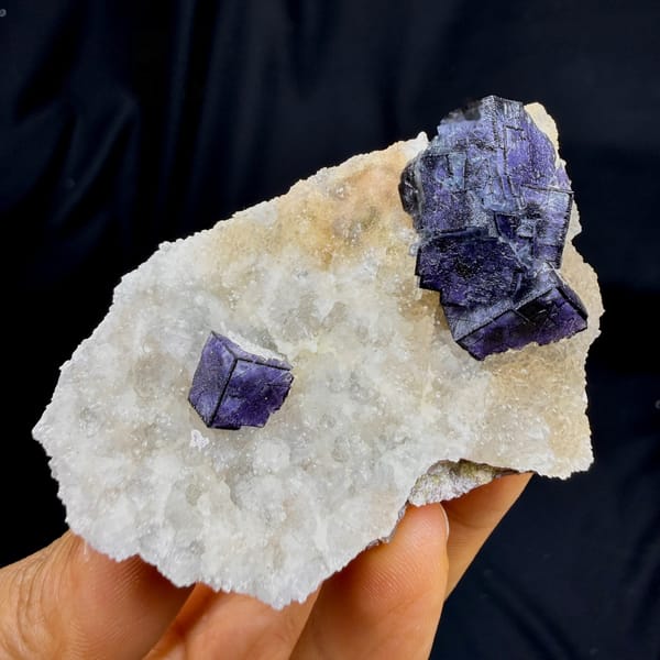 Two deep purple fluorite cubes on white quartz plate from Inner Mongolia, China, detail of the matrix contact