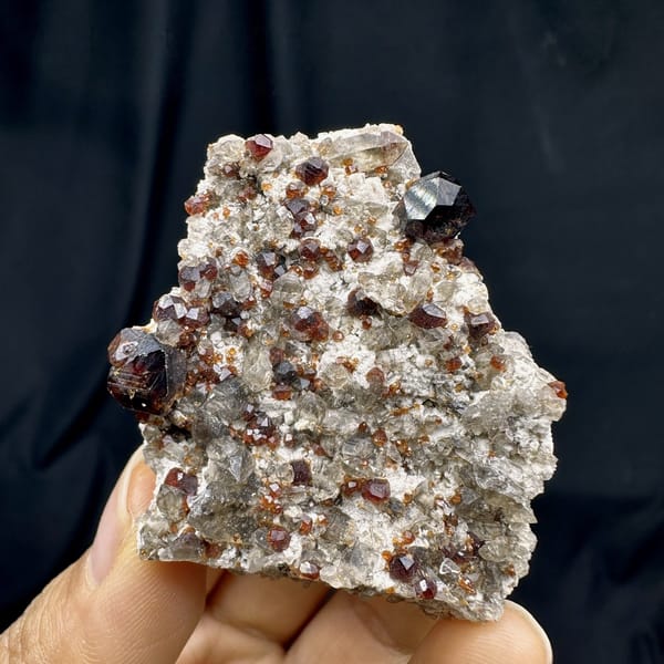 Wine-red garnets crowding cream feldspar with smoky quartz from Yunxiao, Fujian, China, detail of the matrix contact