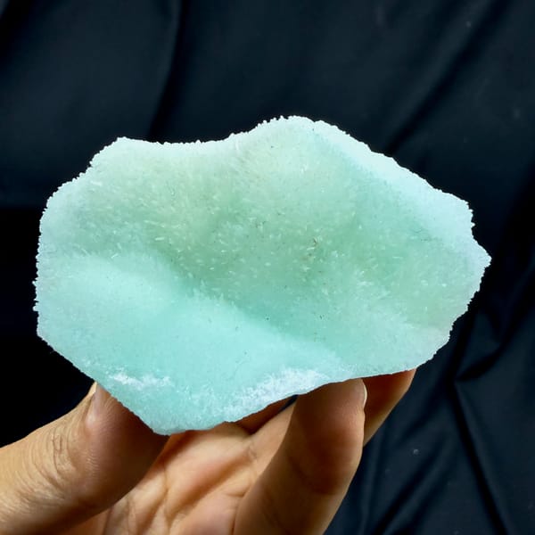 Flat aqua-green acicular aragonite plate from Yunnan, China, held in hand