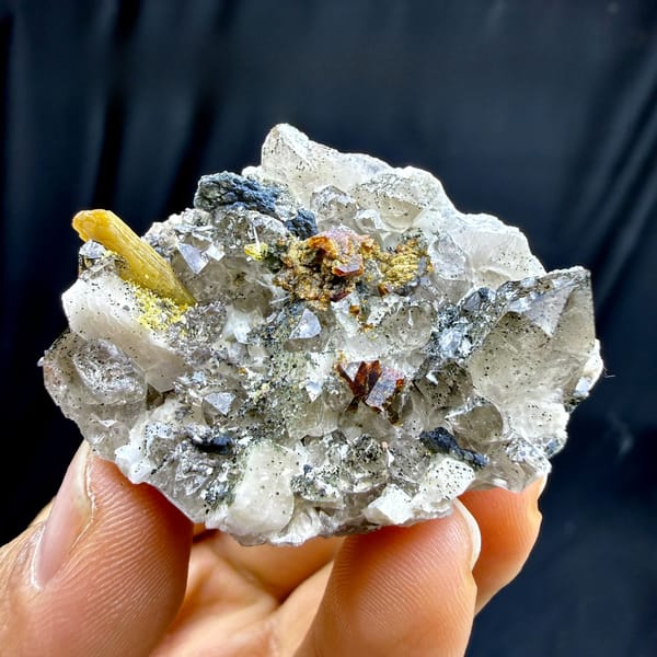 Quartz and feldspar plate with golden helvine crystal from Yunxiao, Fujian, China, held in hand
