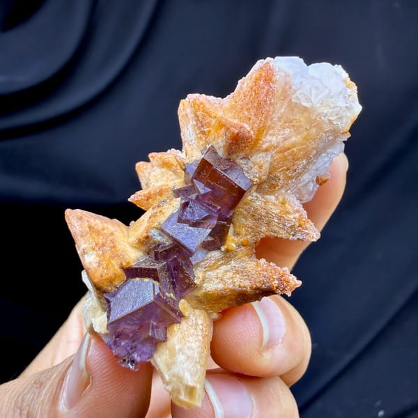 Purple-red fluorite cubes between tan calcite blades from Yunnan, China, close-up of the crystal faces