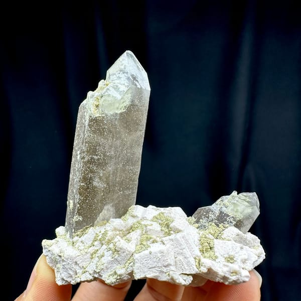 Smoky quartz prism piercing cream feldspar block from Fujian, China, held in hand