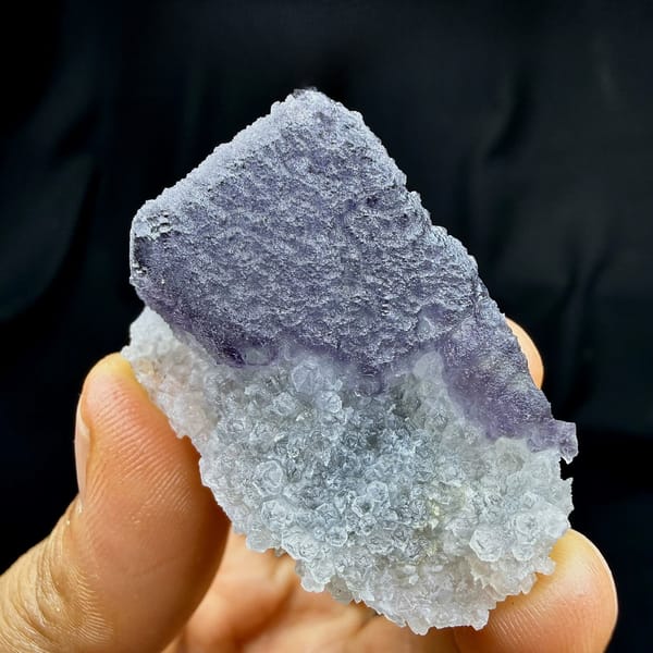 Frosted purple fluorite cube on sparkling white quartz from Fujian, China, held in hand