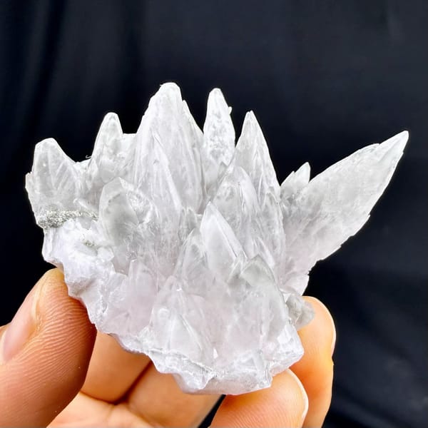 Pale pink feather-calcite crown of pointed blades from Hunan, China, held in hand