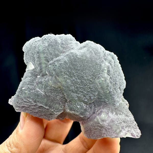 Frosted purple and green fluorite mass with matte skin from Fujian, China, held in hand