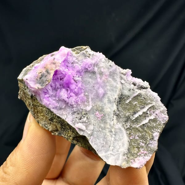 Magenta aragonite patch on pale grey matrix from Yunnan, China, held in hand