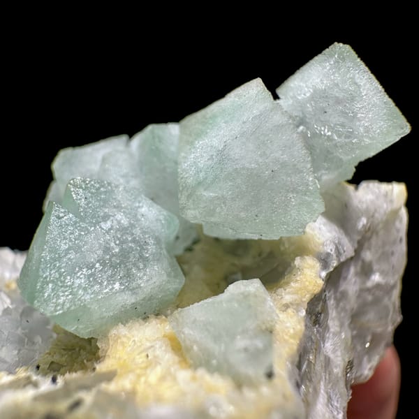 Pale green fluorite octahedra on yellow-crusted matrix from Xianghualing, Hunan, China, close-up of the crystal faces