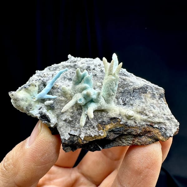 Blue-green stalactitic aragonite fingers on grey rock from Yunnan, China, held in hand