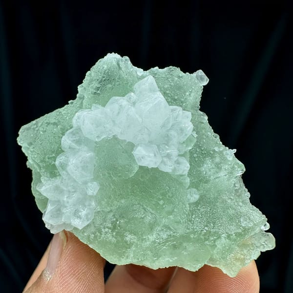 Mint-green fluorite mass with white quartz patch from Guangdong, China, held in hand