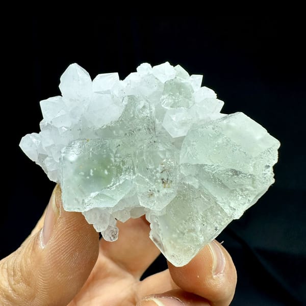 Pale green fluorite cubes with inclusions on white quartz from Guangdong, China, held in hand