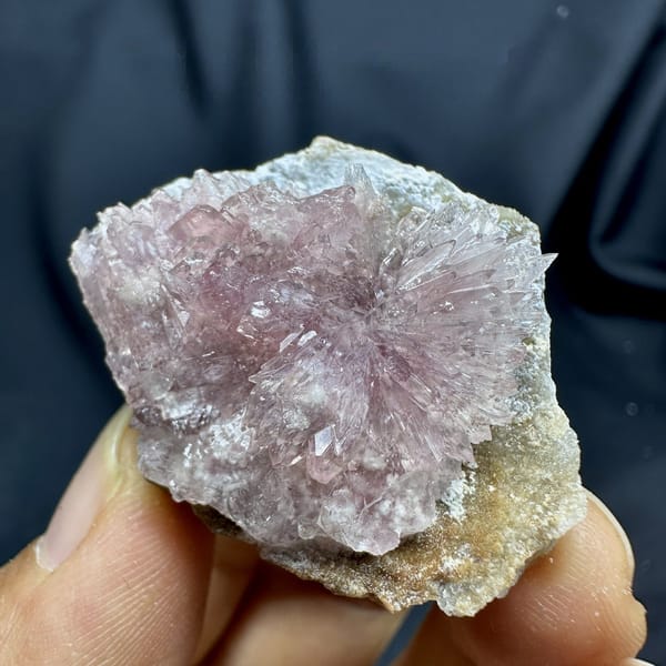 Pink radiating creedite flowers on tan matrix from Guizhou, China, detail of the matrix contact