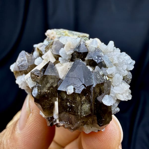 Dark smoky quartz crystals with white feldspar and mica from Yunxiao, Fujian, China, close-up of the crystal faces