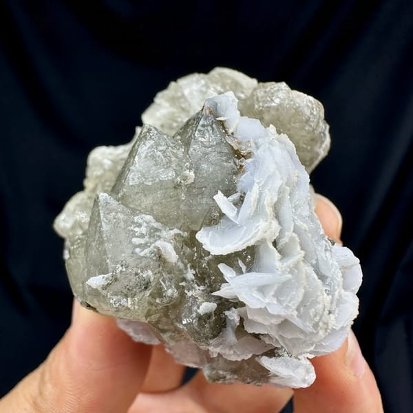 Double-terminated green quartz with calcite plates from Inner Mongolia, China, held in hand