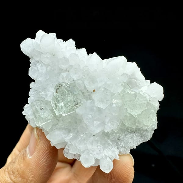 Pale green fluorite cube nested in white quartz points from Guangdong, China, held in hand