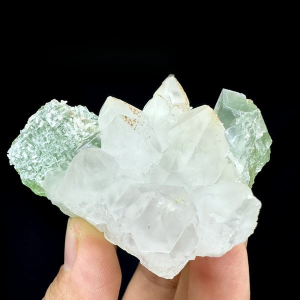 White quartz cluster flanked by mint-green fluorite cubes from Fujian, China, held in hand