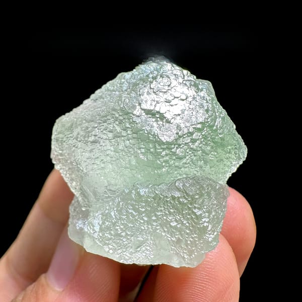 Mint-green stepped fluorite crystal from Xianghualing, Hunan, China, held in hand