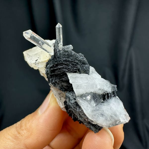 Clear quartz spire on black specular hematite plate from Guangdong, China, close-up of the crystal faces
