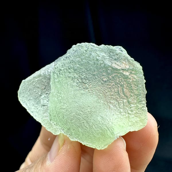 Pale green stepped fluorite with frosted skin from Guangdong, China, held in hand
