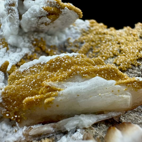 Tan baryte blades with vanadinite druse on white aragonite from Morocco, close-up of the crystal faces