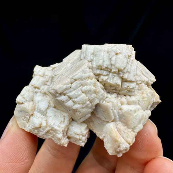 Blocky cream feldspar crystals with small quartz from Yunxiao, Fujian, China, held in hand
