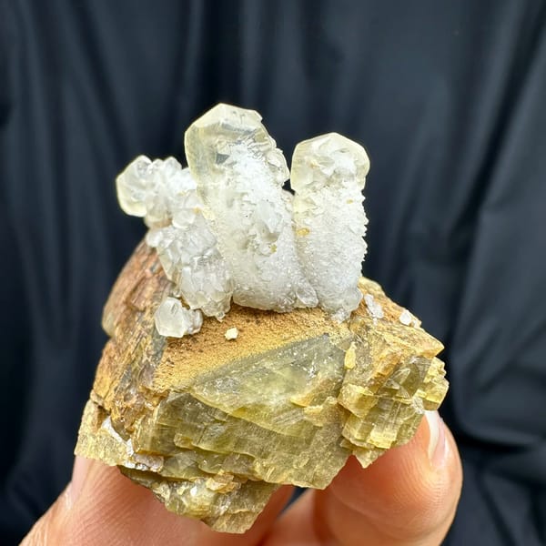 Frosted white calcite prisms on golden siderite block from Guizhou, China, held in hand