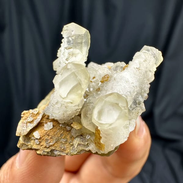 Frosted white calcite prisms on golden siderite block from Guizhou, China, close-up of the crystal faces