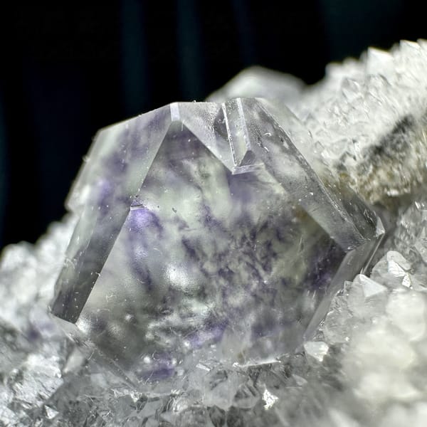 Transparent purple-zoned fluorite dodecahedron on white quartz from Fujian, China, detail of the matrix contact
