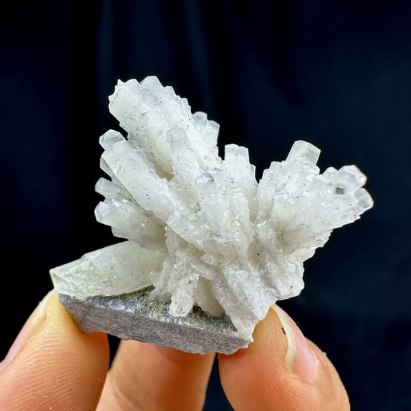 Feather calcite spray, from Shangbao Mine, Hunan, China, front view in daylight, held in hand