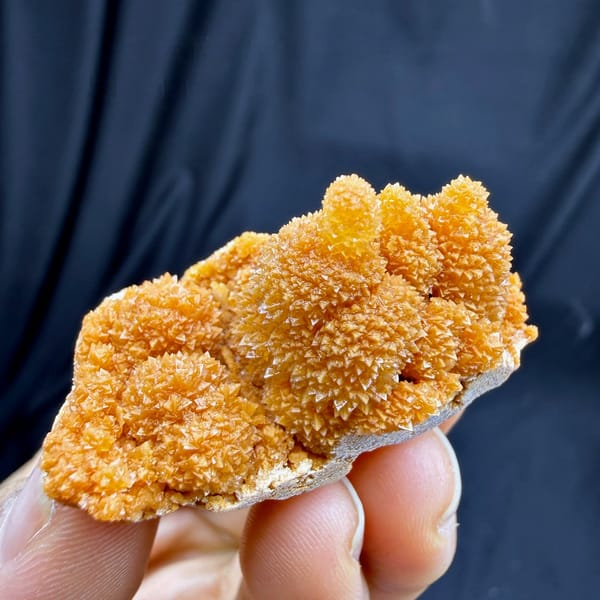 Orange stalactitic calcite mound with sugary skin from Yunnan, China, held in hand