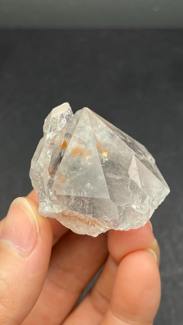 Large clear quartz crystal with rust-orange inclusions from Meigu, Sichuan, China, top view