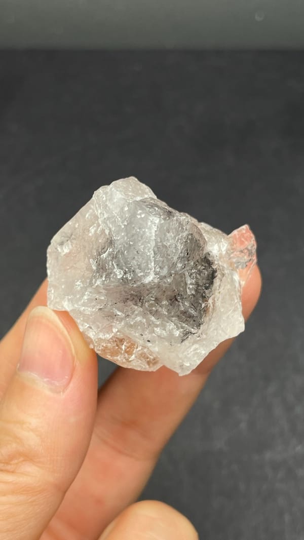 Large clear quartz crystal with rust-orange inclusions from Meigu, Sichuan, China, detail of the matrix contact