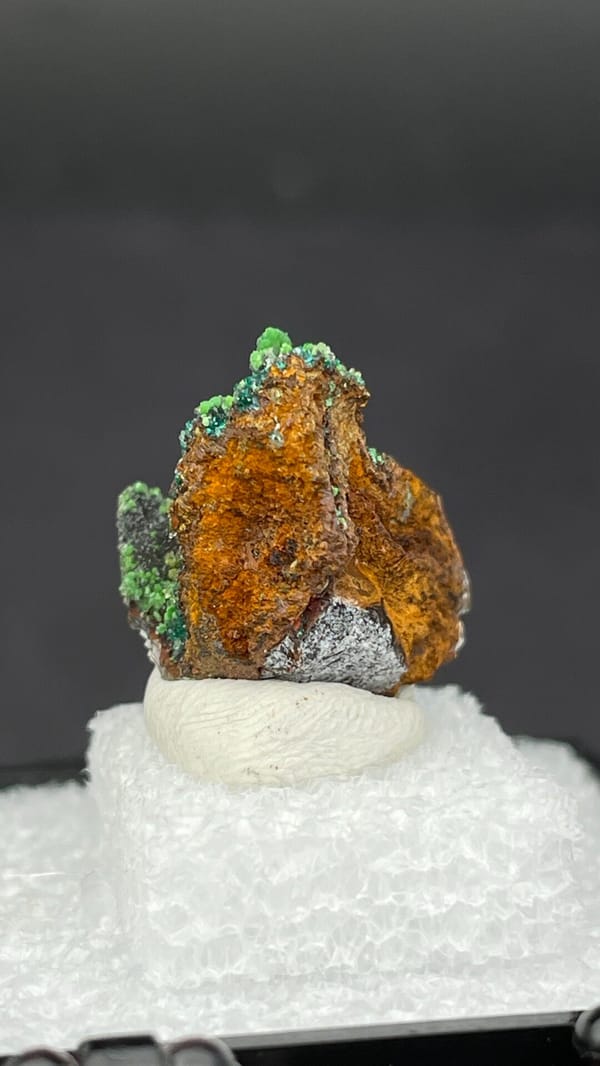 Grass-green botryoidal conichalcite on brown matrix from Morocco, in a box, detail of the matrix contact