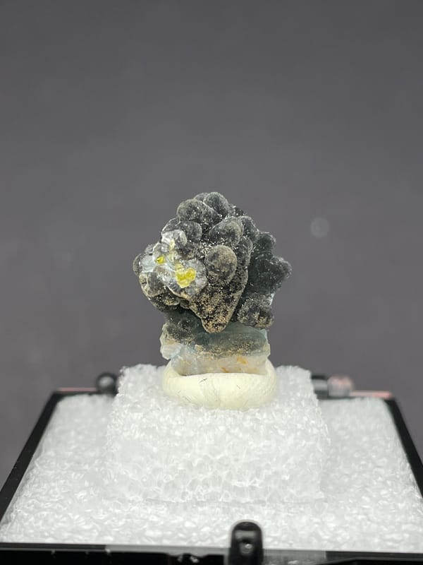 Grey-green botryoidal plumbogummite ball cluster from Guangxi, China, in a box, close-up of the crystal faces