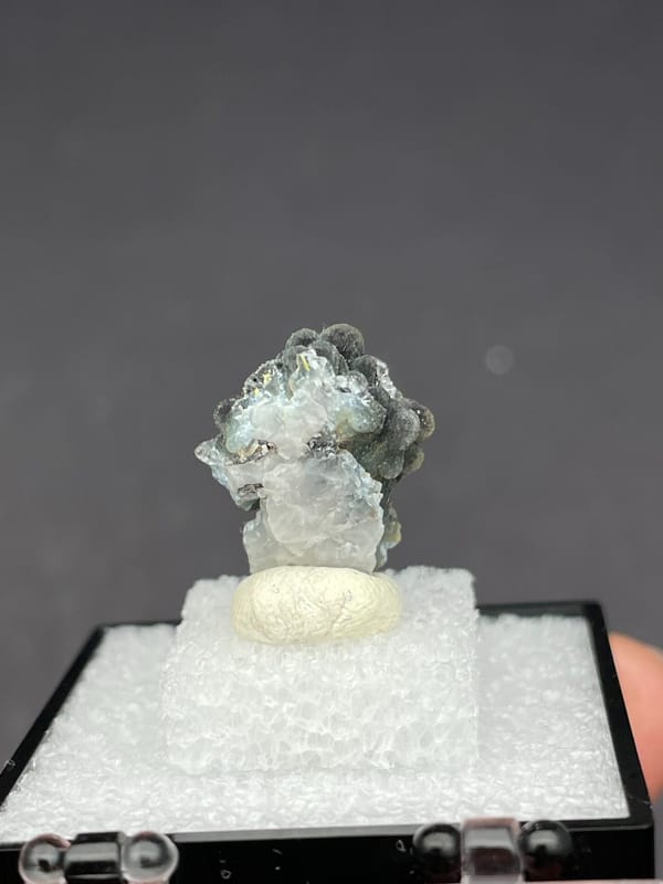 Grey-green botryoidal plumbogummite ball cluster from Guangxi, China, in a box, detail of the matrix contact