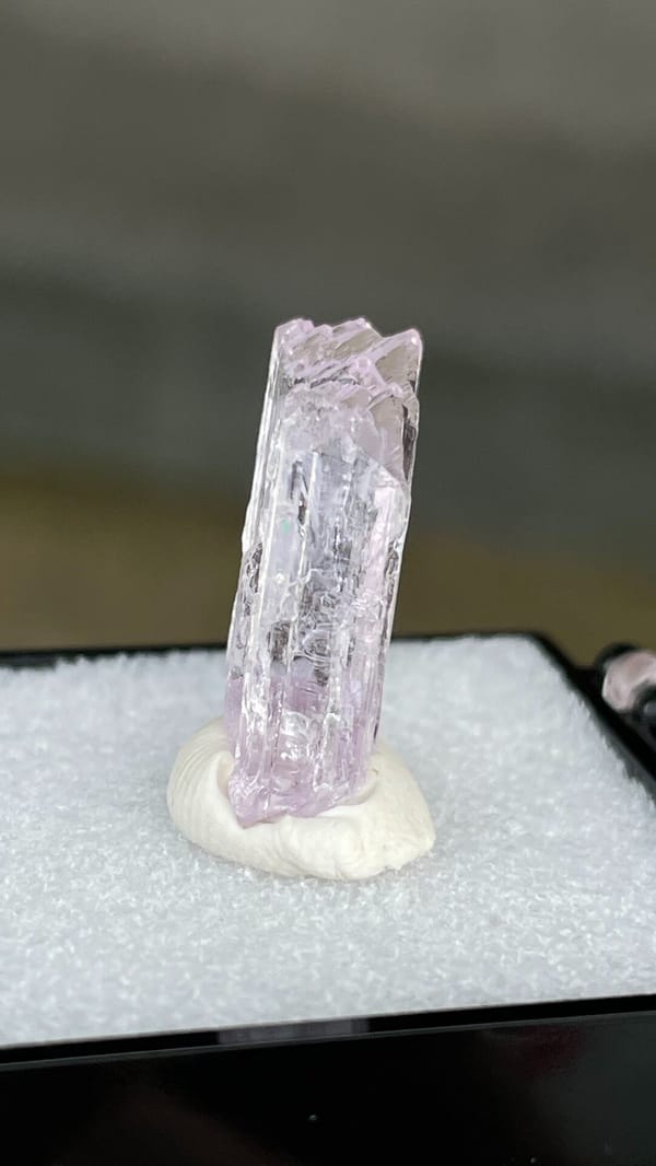 Pale pink bladed kunzite crystal from Afghanistan, mounted on white putty, close-up of the crystal faces
